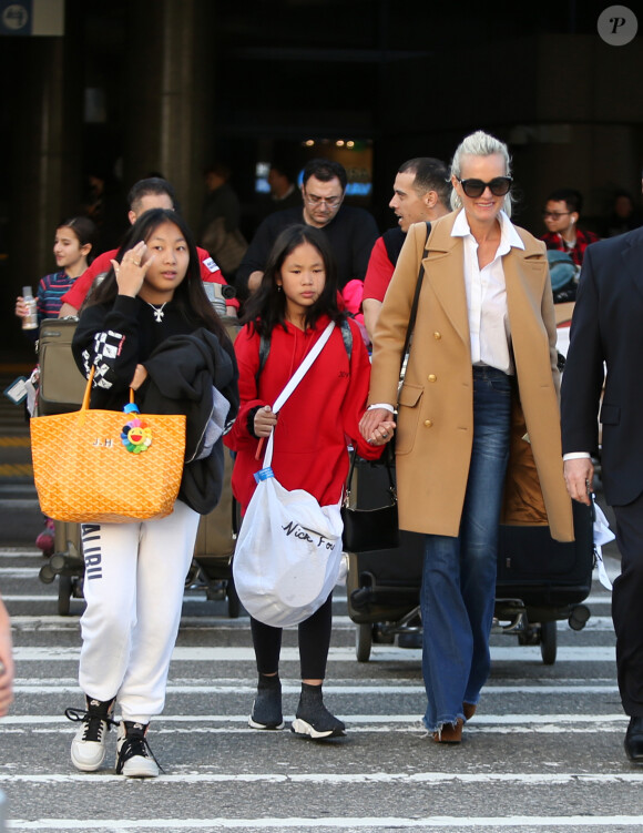 Exclusif - Laeticia Hallyday et ses filles Jade et Joy arrivent à l'aéroport LAX de Los Angeles en provenance de Paris, le samedi 11 janvier 2020 dans l'après-midi. Un chauffeur les attendait à leur arrivée. Laeticia lui fait signe, le salue, puis le suit en compagnie de ses filles jusqu'à la voiture. Deux porteurs poussent ses bagages