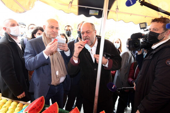 Eric Dupond-Moretti et Laurent Pietraszewski goûtent un morceau de pastèque sur le marché du quartier de la Grande Résidence à Lens le 8 mai 2021.