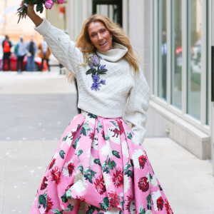 Celine Dion rayonnante et très souriante dans un ensemble pull écru et jupe bouffante fleurie salue ses fans à la sortie de son hôtel à New York, le 8 mars 2020