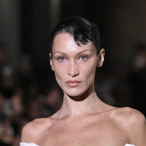 Bella Hadid arrive sur le podium vêtue d'une simple culotte, c'est alors que trois hommes pulvérise une solution sur le mannequin américain et en quelques minutes, une robe minimaliste à manches à épaules dénudées et fente latérale à été créée en clôture du défilé Coperni Collection Femme Prêt-à-porter Printemps/Eté 2023 lors de la Fashion Week de Paris (PWF), France, le 30 septembre 2022. 