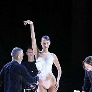 Bella Hadid arrive sur le podium vêtue d'une simple culotte, c'est alors que trois hommes pulvérise une solution sur le mannequin américain et en quelques minutes, une robe minimaliste à manches à épaules dénudées et fente latérale à été créée en clôture du défilé Coperni Collection Femme Prêt-à-porter Printemps/Eté 2023 lors de la Fashion Week de Paris (PWF), France, le 30 septembre 2022. 