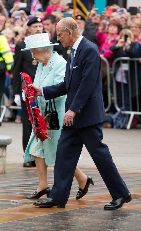 La reine Elisabeth II d'Angleterre et le prince Philip, duc d'Edimbourg déposent une couronne de fleurs devant le monument aux morts de la guerre à Belfast, le 25 juin 2014, lors de leur visite à Belfast. 