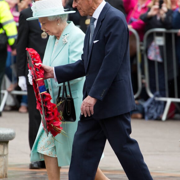 La reine Elisabeth II d'Angleterre et le prince Philip, duc d'Edimbourg déposent une couronne de fleurs devant le monument aux morts de la guerre à Belfast, le 25 juin 2014, lors de leur visite à Belfast. 