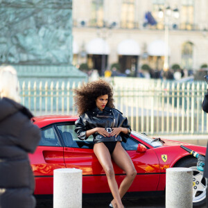 Exclusif - Le mannequin français Tina Kunakey en body et perfecto adossé à une Ferrari 308 lors d'un shooting photo sur la place Vendôme en marge du prêt-à-porter automne-hiver 2023/2024 de la Fashion Week de Paris (PFW) , à Paris, France, le 2 mars 2023. © Da Silva-Perusseau/Bestimage 