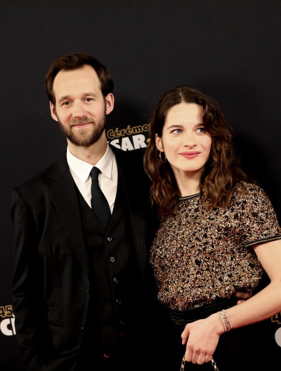 Ils y incarnent un couple qui va devoir préserver un terrible secret alors qu'ils comptent tous les deux parmi les hautes sphères du pouvoir.
Benjamin Lavernhe (en Hermès / Louboutin) et Rebecca Marder (en Chanel) lors du photocall lors de la 45ème cérémonie des César à la salle Pleyel à Paris le 28 février 2020 © Dominique Jacovides / Olivier Borde / Bestimage