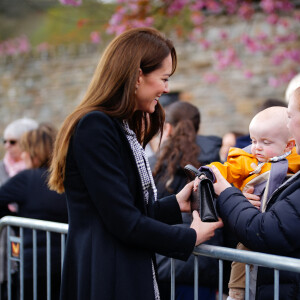 Le jeune Daniel Williams joue avec le sac à main de Catherine (Kate) Middleton, lors de sa visite au jardin commémoratif d'Aberfan, le 28 avril 2023.