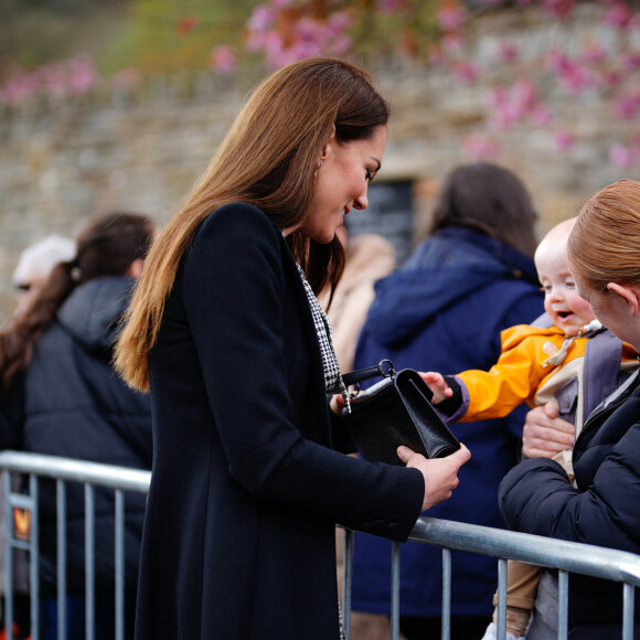 Comme d'habitude, toujours avec le sourire ! 
Le jeune Daniel Williams joue avec le sac à main de Catherine (Kate) Middleton, lors de sa visite au jardin commémoratif d'Aberfan, le 28 avril 2023.
