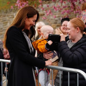 Le jeune Daniel Williams joue avec le sac à main de Catherine (Kate) Middleton, lors de sa visite au jardin commémoratif d'Aberfan, le 28 avril 2023.