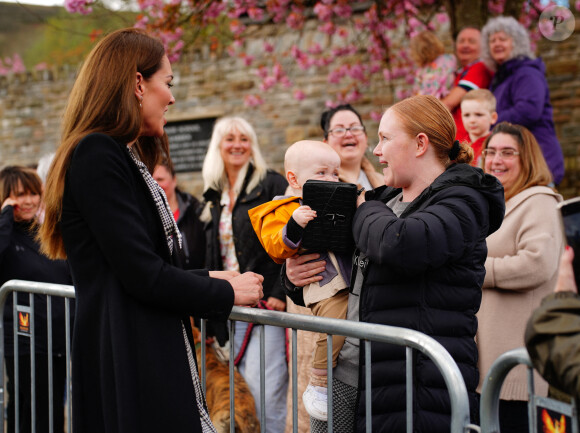 Le jeune Daniel Williams joue avec le sac à main de Catherine (Kate) Middleton, lors de sa visite au jardin commémoratif d'Aberfan, le 28 avril 2023.