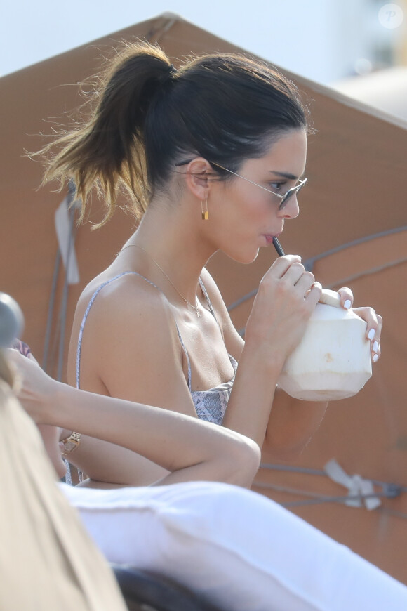 Kendall Jenner sur une plage en train de se délecter d'un jus