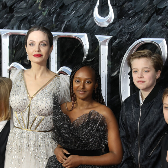 "Pendant que Brad passe des heures à étudier les plans, il arrive qu'Angelina n'arrive pas à canaliser leurs rejetons. Elle les emmenait faire un tour au Leclerc à côté, car elle adore les supermarchés."
Angelina Jolie et ses enfants Vivienne, Zahara, Shiloh et Knox Jolie-Pitt assistent à l'avant-première du film "Maléfique : Le Pouvoir du mal" à l'Imax Odeon de Londres, le 9 octobre 2019.