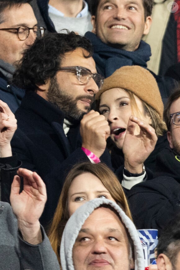 Maxim Nucci (Yodelice) et sa compagne Isabelle Ithurburu dans les tribunes lors du match de rugby du Tournoi des 6 Nations opposant la France à l'Angleterre au stade de France, à Saint-Denis, Seine Saint-Denis, France, le 19 mars 2022. La France s'offre le grand chelem dans le Tournoi des six nations, après sa victoire 25-13 contre l'Angleterre. © Cyril Moreau/Bestimage