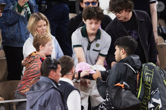 Le chanteur Raphaël, sa compagne Mélanie Thierry et leurs enfants Roman et Aliocha Haroche demandent une dédicace sur leurs casquettes à Carlos Alcaraz - Célébrités dans les tribunes des Internationaux de France de tennis de Roland Garros 2024 à Paris, le 29 mai 2024. © Moreau / Jacovides / Bestimage 