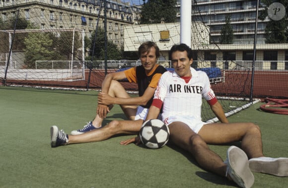 Archives - No web - En France, à Paris, Jean-Loup LAFONT et Didier ROUSTAN assis sur un stade en tenue sportive ensemble un ballon de foot au pied. 