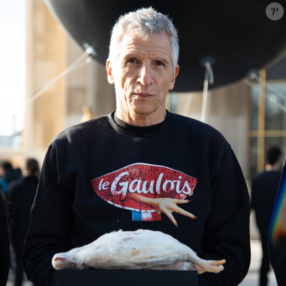 L'animateur Nagui tient un poulet mort avec une banderole indiquant son âge et son poids au moment de sa mort lors d'une manifestation appelée par l'association française de défense des animaux L214 sur l'esplanade des Droits de l'Homme du Trocadéro à Paris, le 15 février 2024, pour sensibiliser et dénoncer l'utilisation de poulets génétiquement manipulés par l'entreprise agroalimentaire française "Le Gaulois". Photo par Florian Poitout/ABACAPRESS.COM