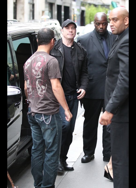 John Travolta, entouré de gardes du corps, s'apprête à entrer dans le restaurant asiatique Dave à Paris le 20 juin 2011