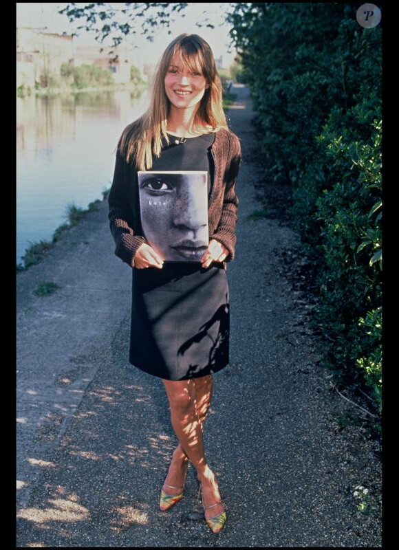 Kate Moss, sourire aux lèvres, son book entre les mains. Au Royaume-Uni, 1995.