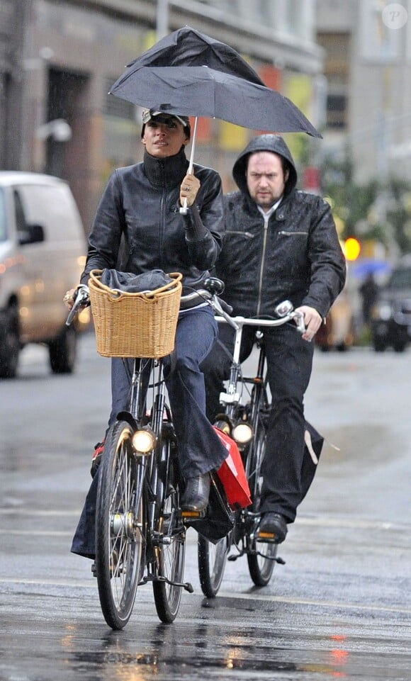 Famke Janssen à vélo, mais avec un parapluie