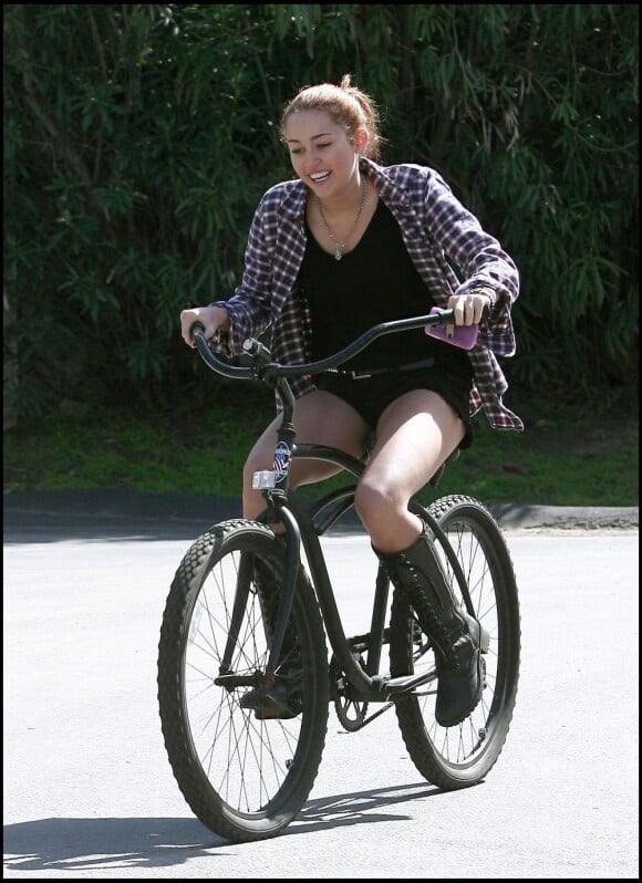 Miley Cyrus à velo, morte de rire avec ses bottes