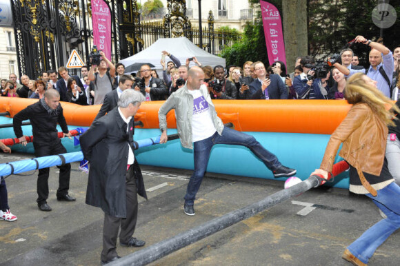 Zinedine Zidane et Sophie Thalmann s'essaient au babyfoot géant le 7 juin 2012 lors d'une journée de mobilisation organisée par ELA dans les rues de Paris près du Parc Monceau