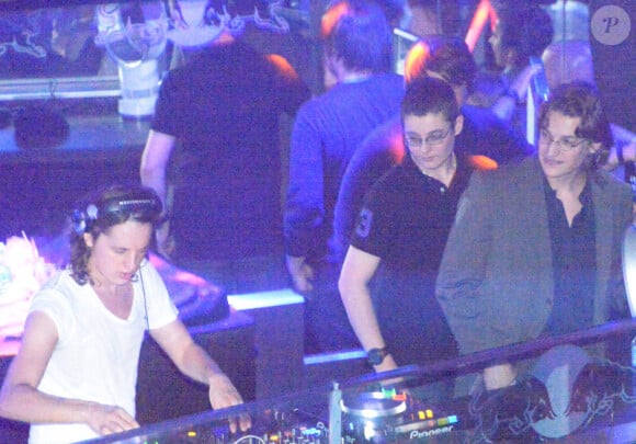 Pierre Sarkozy, alias DJ Mosey, mixe pendant que ses frères Louis et Jean l'observent lors de la soirée au Queen, boîte de nuit des Champs-Elysées à Paris, le 22 juin 2012