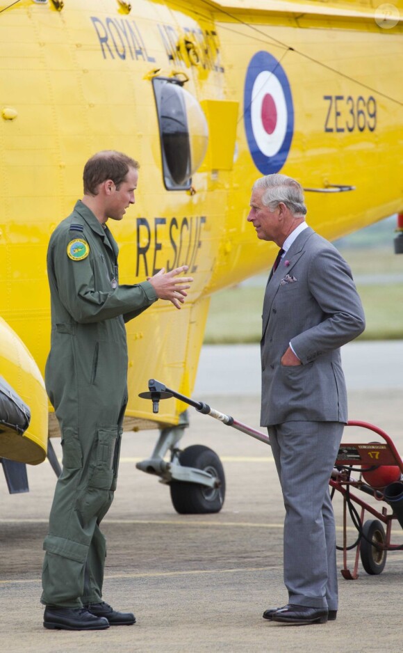 Visite guidée de la base de la RAF Valley à Anglesey pour le prince Charles, très attentif, par son fils le prince William, capitaine au sein du 22e escadron, le 9 juillet 2012, au premier jour de sa tournée au Pays de Galles.
