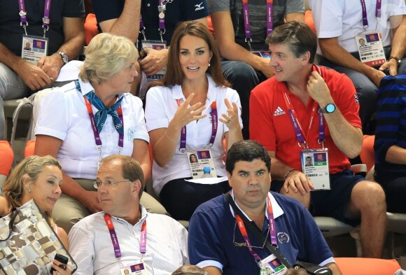 Kate Middleton, entre les anciennes gloires britanniques du patinage artistique Jenny Gray et Robin Cousins, dans les gradins de l'Aquatics Centre le 9 août 2012 pour soutenir et applaudir les nageuses britanniques en lice en natation synchronisée par équipes. La Grande-Bretagne a fini 6e.