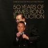 Sir Roger Moore s'éclate avec un masque de Daniel Craig ! Vente aux enchères d'objets de la saga James Bond donnés par les acteurs de la franchise, chez Christie's, à Londres, le 5 octobre 2012