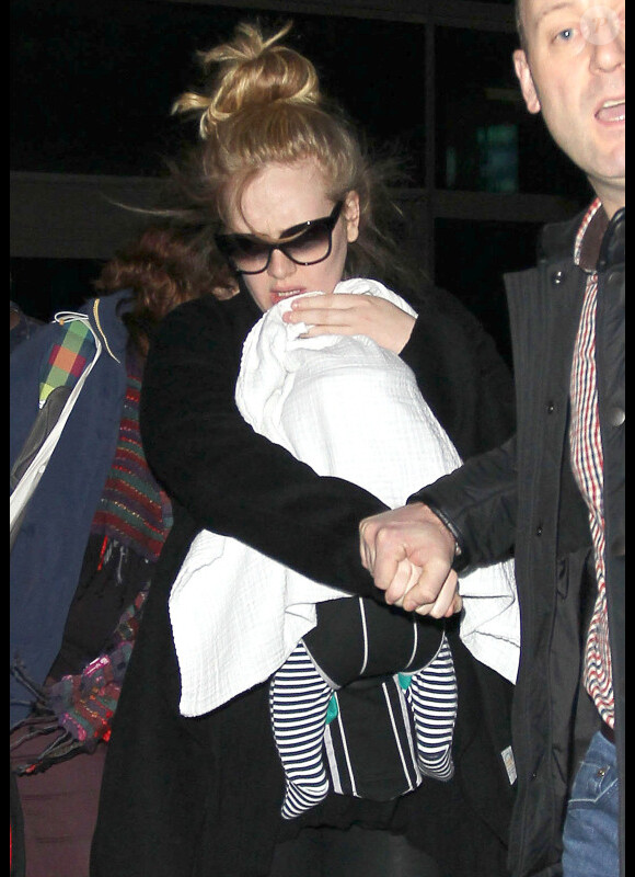 Arrivée tumultueuse de la chanteuse Adele qui essaie de protéger son nouveau-né des photographes et de la foule, à l'aéroport de Los Angeles, le 10 janvier 2013.
