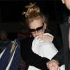 Arrivée tumultueuse pour la chanteuse Adele qui essaie de protéger son nouveau-né des photographes et de la foule, à l'aéroport de Los Angeles, le 10 janvier 2013.