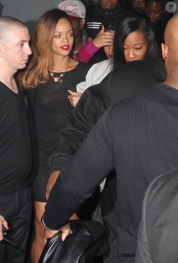 Rihanna, souriante et épanouie, quitte le Playhouse, une boîte de nuit de Los Angeles, au bras de son amie Melissa, le 24 janvier 2013. Rihanna arbore une robe très courte noire transparente sans soutien-gorge sur de somptueux talons.