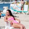 En monokini rose et rarement sans un verre à la main, Tulisa Contostavlos ne risque pas de passer inaperçue à la plage, en vacances à Ibiza le 10 juillet 2013