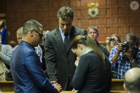 Avant l'arrivée du juge, Oscar Pistorius prie avec son frère et sa soeur au tribunal de Pretoria le 19 août 2013.