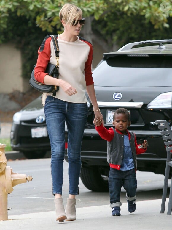 Charlize Theron, craquante en compagnie de son fils Jackson à Los Angeles, porte des lunettes Stella McCartney, un sac Tom Ford, un jean Current/Elliott et des bottines Rag & Bone. Le 20 Septembre 2013.