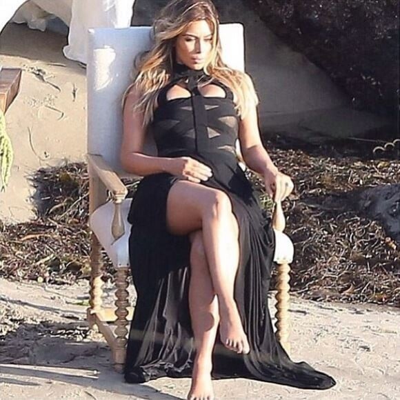 Kim Kardashian, canon dans sa robe Alexander McQueen lors d'un shooting photo sur une plage.