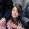 Suri Cruise, souriante, déguste un esquimau alors qu'elle se promène avec sa nounou et son garde du corps à New York, le 11 décembre 2013.