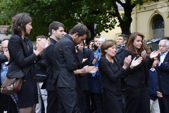 Elisabeth Duquesne, veuve de Benoît Duquesne, et leurs quatre enfants ont applaudi avec une immense émotion et beaucoup de fierté à la sortie du cercueil lors des obsèques du journaliste, à l'église Jeanne d'Arc de Versailles, le jeudi 10 juillet 2014.