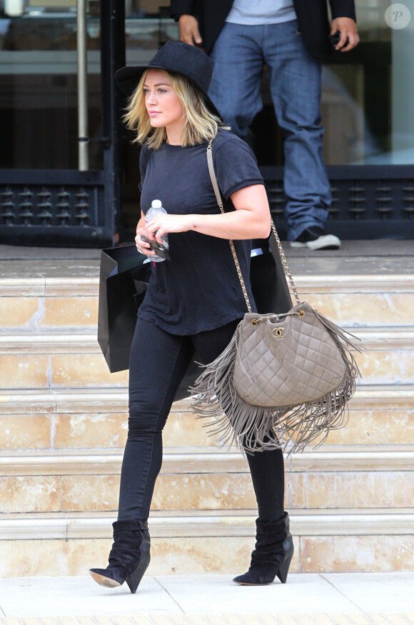 Hilary Duff quitte le centre commercial Barneys New York à Beverly Hills, tout de noir vêtue avec un sac à franges Chanel et des bottines Isabel Marant (modèle Andrew). Los Angeles, le 3 août 2014.