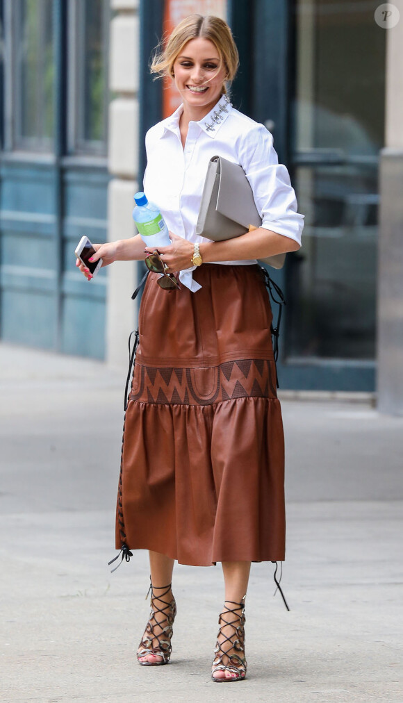 Olivia Palermo, radieuse à New York, porte une chemise blanche ornée au col, une jupe en cuir vintage et des sandales lacées Altuzarra. Le 4 août 2014.