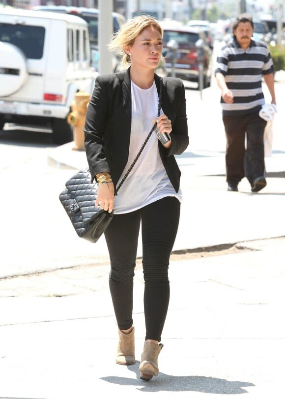 Hilary Duff se promène à West Hollywood, habillée d'un blazer noir Helmut Lang, d'un t-shirt blanc, d'un sac matelassé Chanel, d'un jean nervuré aux genoux Frame Denim et de bottines Belle by Sigerson Morrison. Le 20 août 2014.