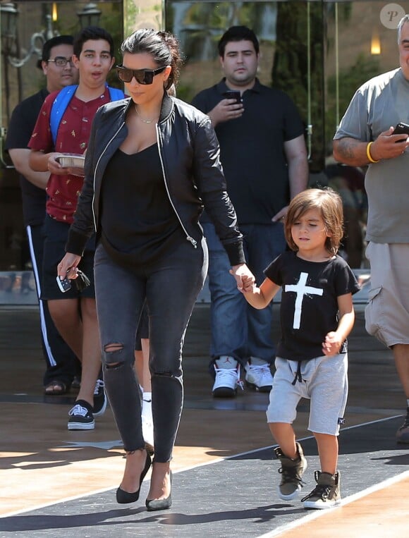 Kim Kardashian quitte les cinémas Edwards Calabasas Stadium 6 avec son neveu Mason Disick, habillée de lunettes Céline, d'un bomber et d'un t-shirt noir, d'un jean J Brand et de souliers Saint Laurent. Calabasas, le 19 août 2014.