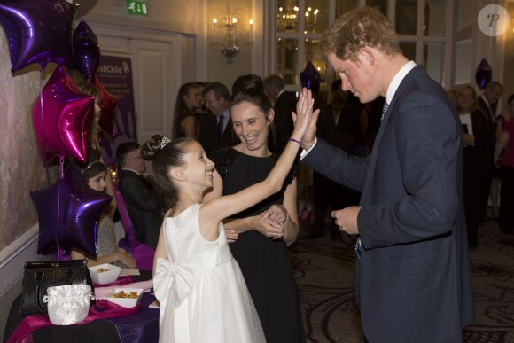 Le prince Harry "high-five" une jeune lauréate lors de la cérémonie des 10e WellChild Awards, le 22 septembre 2014 au Hilton de Londres, remis par l'association WellChild qui soutient les enfants malades, dont il est le parrain depuis 2007.