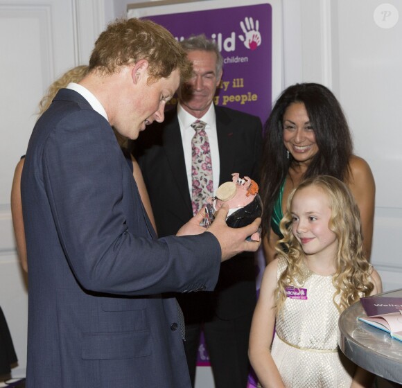 Le prince Harry ravi de recevoir en cadeau une tirelire de cochon à son image lors de la cérémonie des 10e WellChild Awards, le 22 septembre 2014 au Hilton de Londres, remis par l'association WellChild qui soutient les enfants malades, dont il est le parrain depuis 2007.