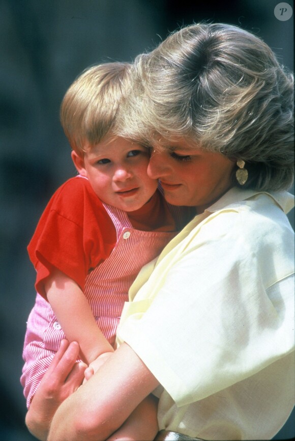 Le prince Harry, un mois avant son 3e anniversaire, dans les bras de sa mère Lady Di en août 1987 à Majorque.