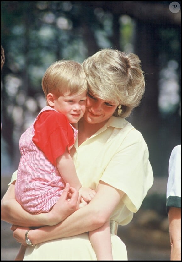 Le prince Harry, un mois avant son 3e anniversaire, dans les bras de sa mère Lady Di en août 1987 à Palma de Majorque.