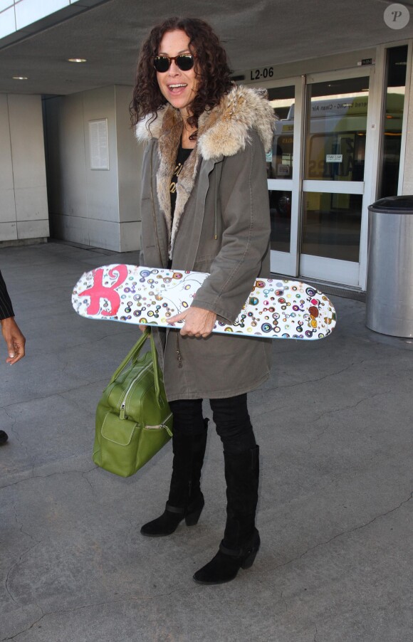 Minnie Driver à l'aéroport de Los Angeles avec une planche de skate le 17 novembre 2014. 