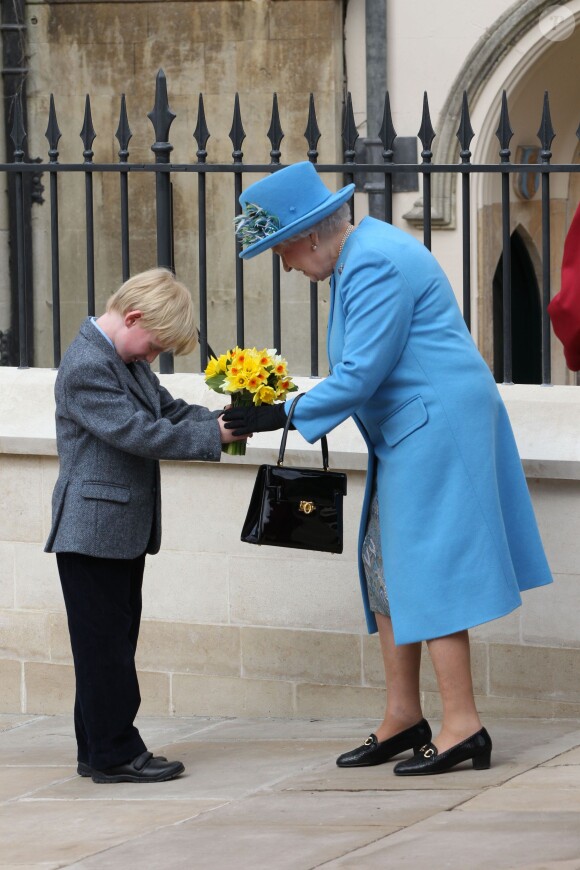 La reine Elizabeth II reçoit des jonquilles lors de la messe de Pâques en la chapelle St George à Windsor le 5 avril 2015.