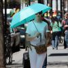Anne Hathaway se protège du soleil avec un parapluie dans la rue à New York, le 29 avril 2015. 
