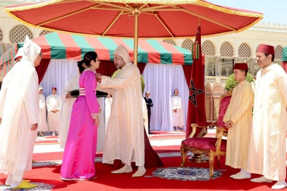 Le roi Mohammed VI du Maroc remettant les ouissams royaux, sous l'oeil de son fils le prince héritier Moulay El Hassan et de son frère le prince Moulay Rachi, le 30 juillet 2015 au palais royal, à Rabat, pour la Fête du Trône à l'occasion du 16e anniversaire de son règne.