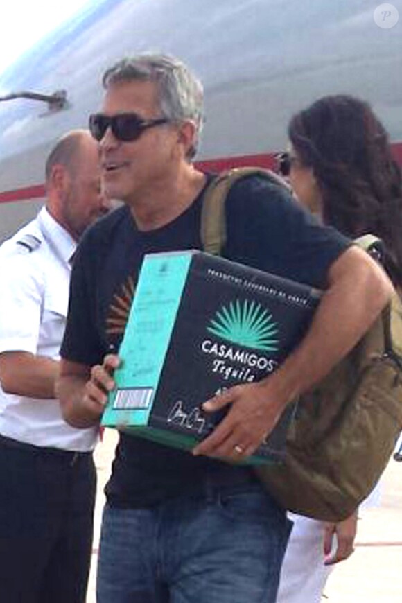Exclusif - George Clooney et sa femme Amal Alamuddin Clooney débarquent d'un jet à Ibiza en compagnie de Cindy Crawford et son mari Rande Gerber le 22 août 2015. Il descend de l'avion avec un carton de sa Tequila "Casamigos" sous le bras.